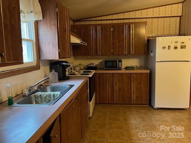 kitchen featuring white fridge, vaulted ceiling, range with electric stovetop, and sink