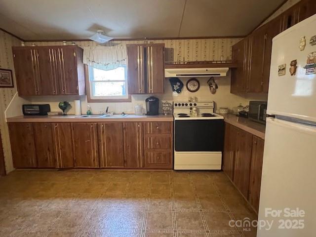 kitchen with white appliances, sink, and exhaust hood