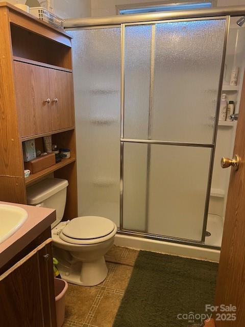 bathroom featuring vanity, toilet, and a shower with door