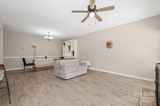 living room with ceiling fan with notable chandelier, baseboards, and light wood-style floors