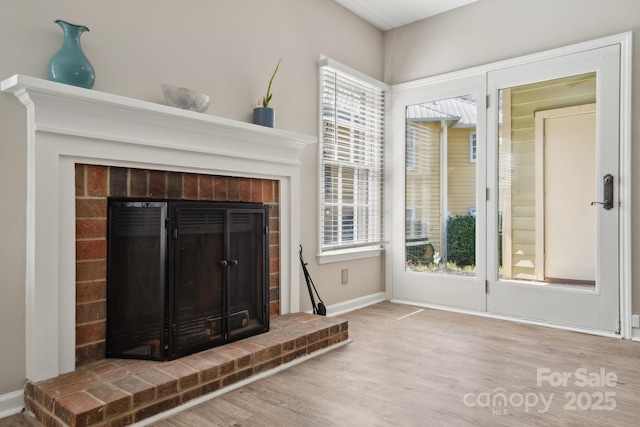 interior details with a brick fireplace, baseboards, and wood finished floors