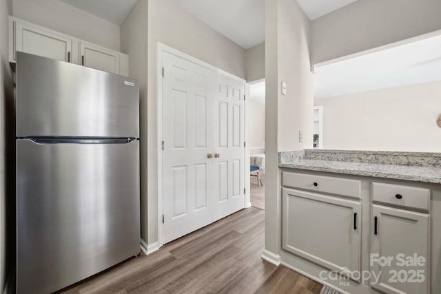 kitchen with dark wood finished floors, light stone countertops, and freestanding refrigerator