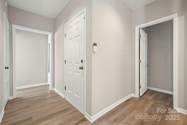 corridor with baseboards and light wood-type flooring