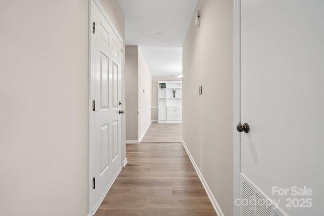 hall with visible vents, baseboards, and wood finished floors