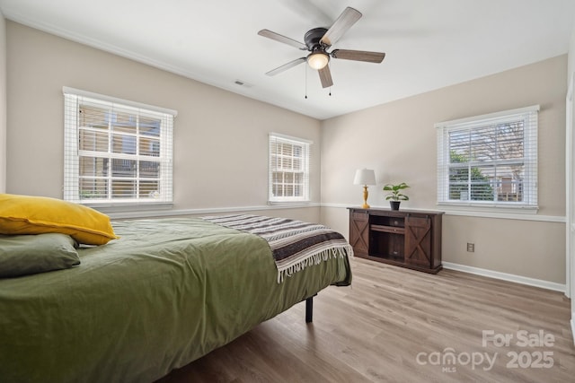 bedroom with visible vents, multiple windows, baseboards, and wood finished floors