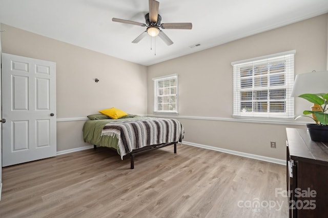 bedroom with light wood finished floors, visible vents, a ceiling fan, and baseboards