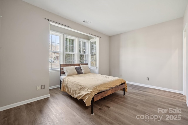 bedroom with visible vents, baseboards, and wood finished floors