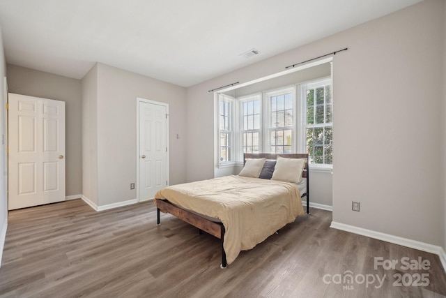 bedroom featuring visible vents, baseboards, and wood finished floors