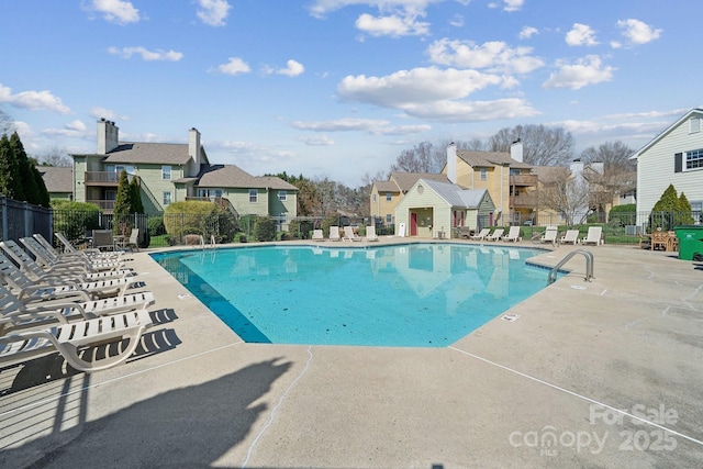 community pool with a patio area, fence, and a residential view