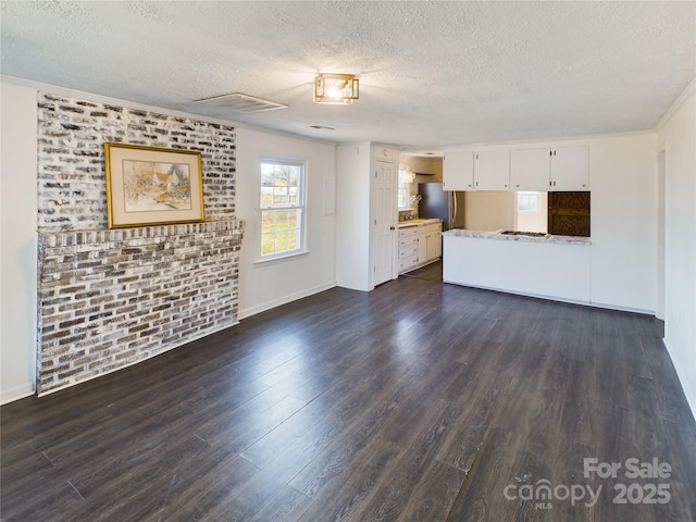 unfurnished living room with dark hardwood / wood-style floors, a textured ceiling, and brick wall