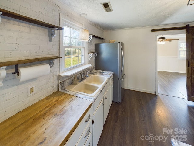 kitchen with sink, dark wood-type flooring, a textured ceiling, decorative light fixtures, and white cabinets