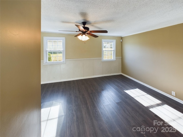 spare room featuring a textured ceiling, ceiling fan, a healthy amount of sunlight, and dark hardwood / wood-style floors