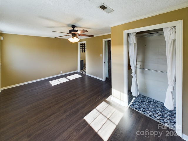 interior space featuring ceiling fan, dark hardwood / wood-style floors, a textured ceiling, and ornamental molding