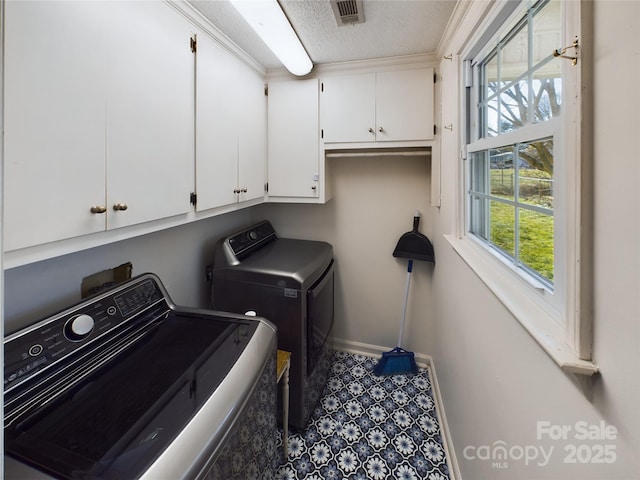 laundry room with cabinets, a textured ceiling, and washing machine and clothes dryer