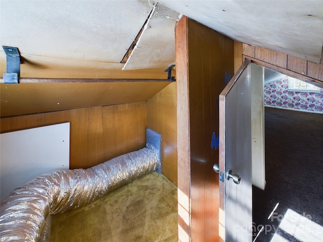 additional living space featuring dark colored carpet, lofted ceiling, and wooden walls