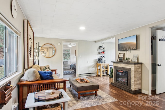 living room featuring ceiling fan with notable chandelier, a baseboard radiator, and dark wood-type flooring