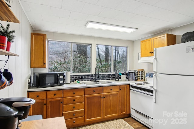 kitchen with hardwood / wood-style flooring, white appliances, sink, and tasteful backsplash