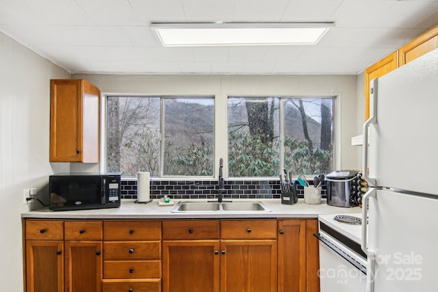 kitchen featuring decorative backsplash, range, white refrigerator, and sink