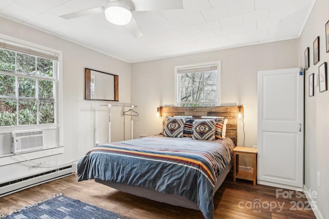 bedroom with ceiling fan, dark hardwood / wood-style floors, a baseboard heating unit, cooling unit, and ornamental molding