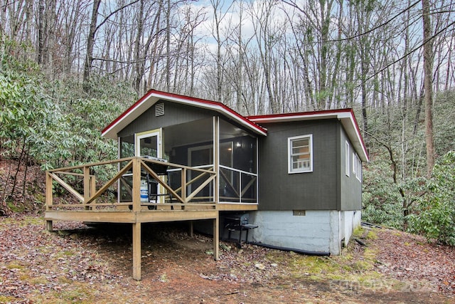 rear view of property featuring a sunroom and a wooden deck