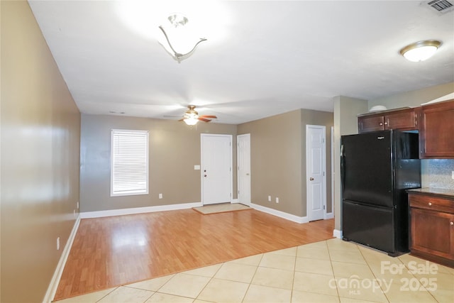 kitchen with black fridge, light tile patterned flooring, and ceiling fan