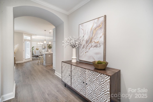 hallway with light wood-type flooring, crown molding, and a chandelier