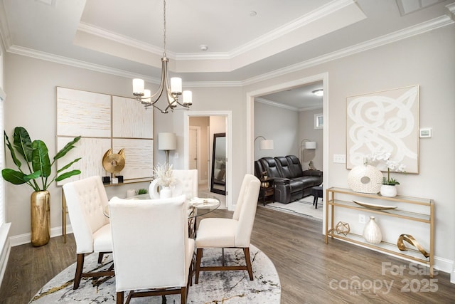 dining space featuring a tray ceiling, dark hardwood / wood-style flooring, and a notable chandelier