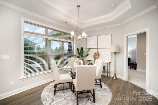 dining area with a raised ceiling, dark hardwood / wood-style flooring, plenty of natural light, and a notable chandelier