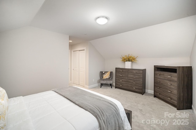 bedroom with a closet, light colored carpet, and lofted ceiling