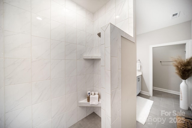 bathroom with a tile shower, tile patterned floors, and vanity