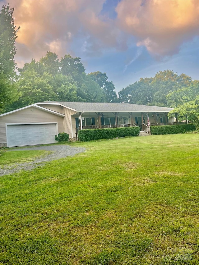 view of front of house with driveway, covered porch, and a yard