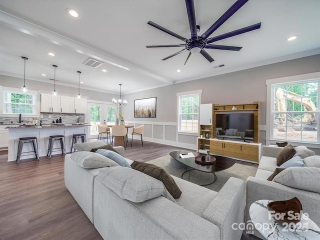 living room featuring crown molding, hardwood / wood-style floors, beamed ceiling, and ceiling fan with notable chandelier