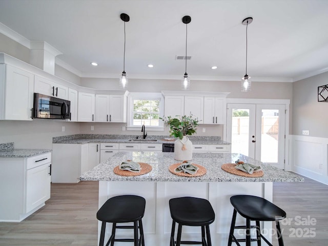 kitchen with white cabinets, a kitchen island, sink, and french doors