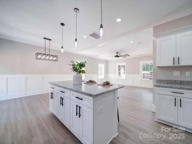 kitchen featuring light stone countertops, decorative light fixtures, and white cabinetry