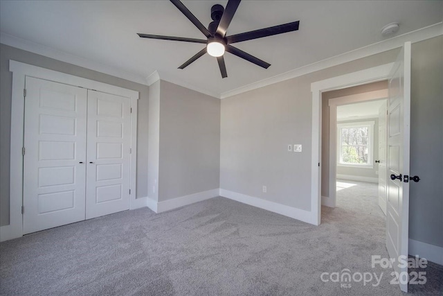 unfurnished bedroom with ceiling fan, a closet, light carpet, and ornamental molding