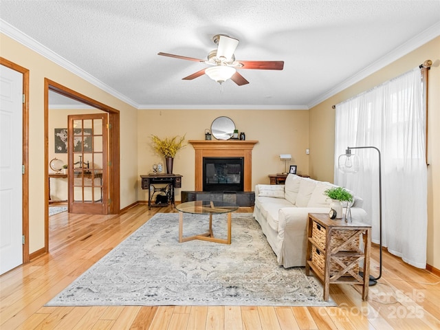 living room with a tiled fireplace, crown molding, light hardwood / wood-style floors, and a textured ceiling