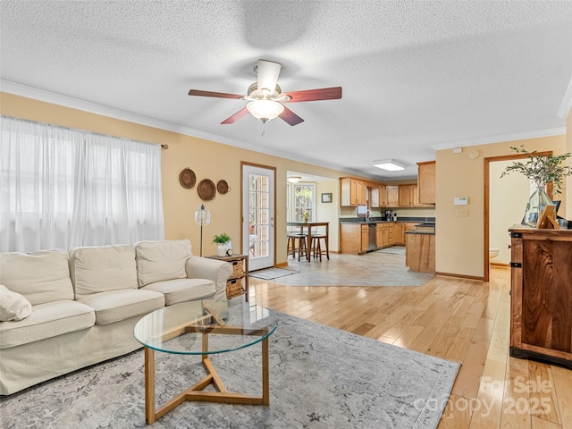 living room featuring a textured ceiling, light hardwood / wood-style flooring, ceiling fan, and crown molding