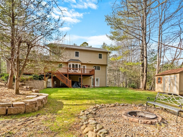 back of property featuring a lawn, a storage unit, a fire pit, and a deck