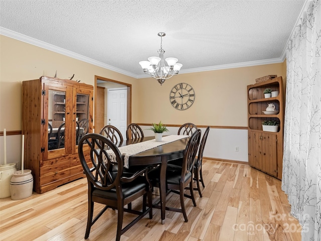 dining space featuring light hardwood / wood-style flooring, crown molding, and a notable chandelier