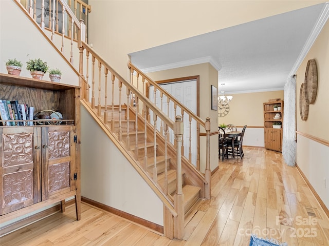 stairs with a chandelier, ornamental molding, and hardwood / wood-style flooring