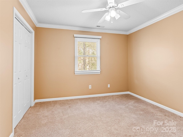 unfurnished bedroom with light carpet, ornamental molding, a textured ceiling, ceiling fan, and a closet