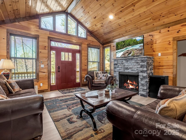 living room with wood walls, a stone fireplace, wood ceiling, and a healthy amount of sunlight