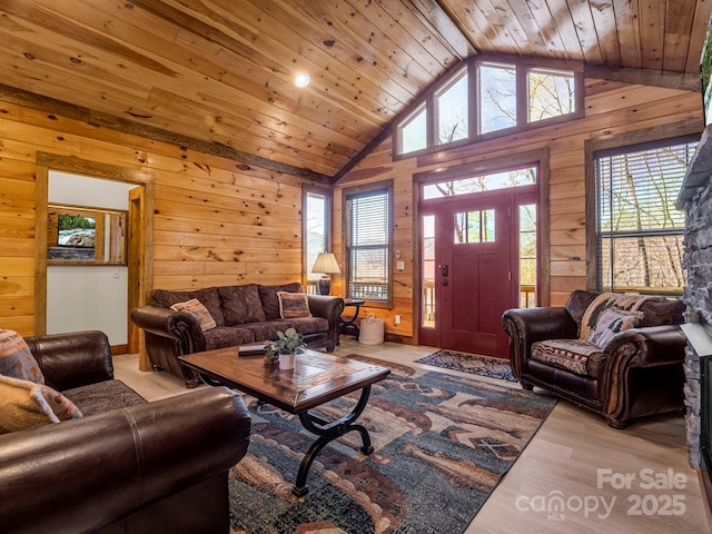 living room featuring light hardwood / wood-style floors, wood walls, wooden ceiling, and high vaulted ceiling