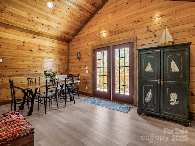 interior space featuring french doors, wood walls, vaulted ceiling, wood ceiling, and light wood-type flooring