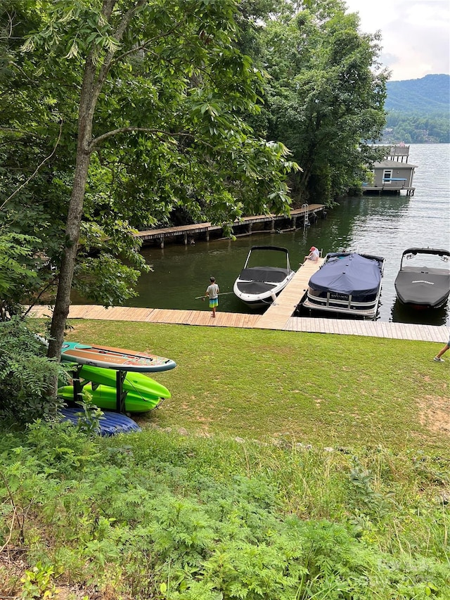 view of dock with a water view and a lawn