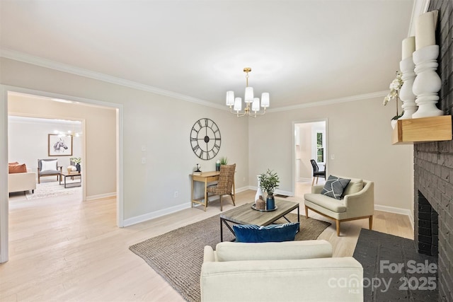 living room with a notable chandelier, light wood-type flooring, ornamental molding, and a fireplace