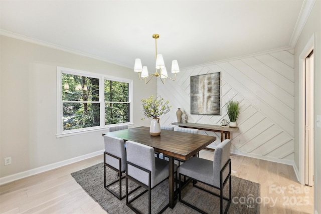 dining area with light wood-type flooring, an inviting chandelier, and crown molding