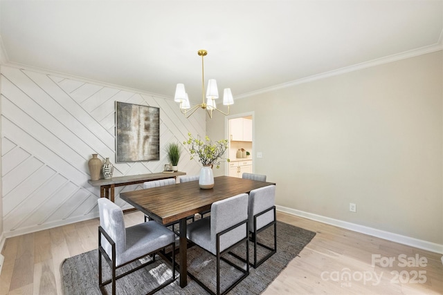 dining room with ornamental molding, a notable chandelier, and light wood-type flooring