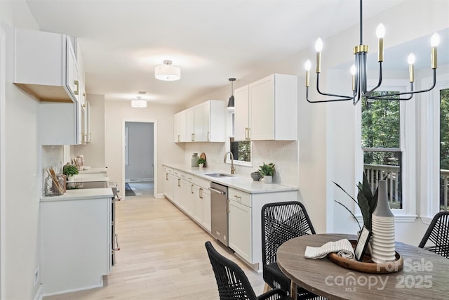 kitchen with sink, white cabinets, hanging light fixtures, and stainless steel dishwasher