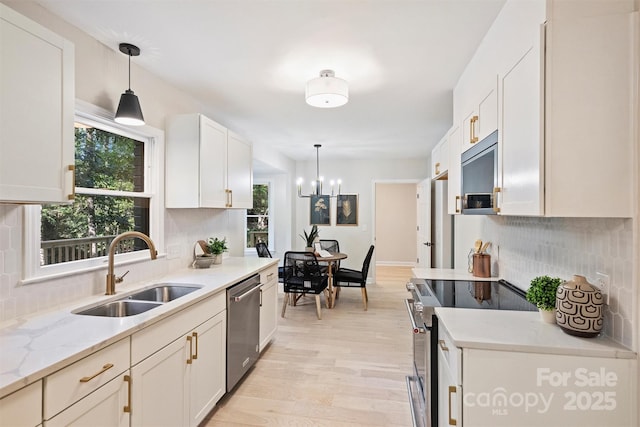 kitchen featuring light stone countertops, stainless steel appliances, hanging light fixtures, and sink